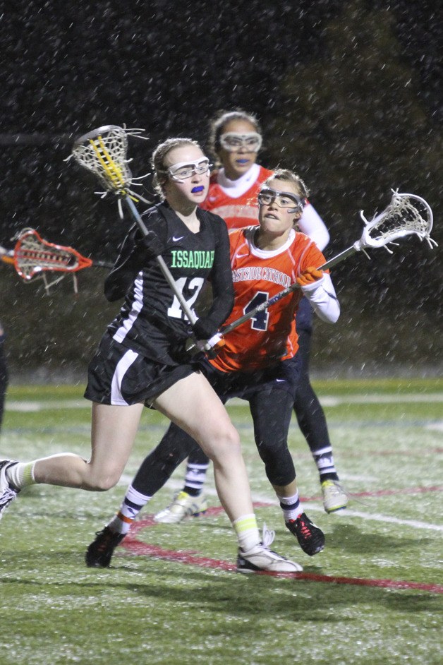 Issaquah's Robin Ringman (#12 black) is checked by Eastside Catholic's Lauren Breynaert (#4 orange) in opening-night lacrosse action