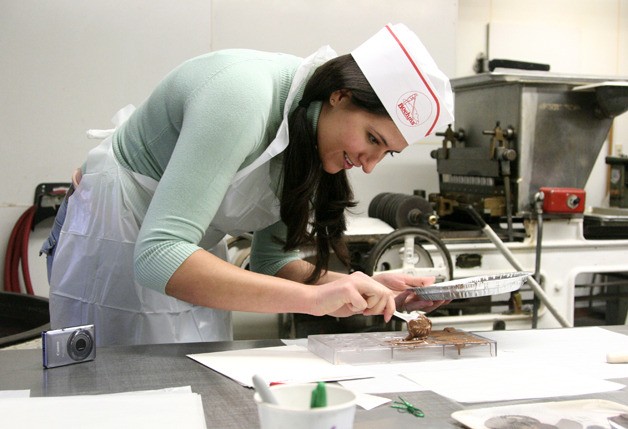 Lorette Cisneros fills molds with milk chocolate in the candy kitchen at Boehm's Candies as a part of a chocolate making class.