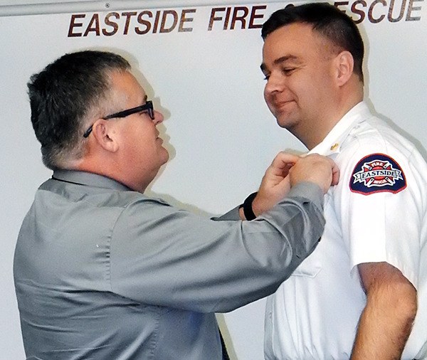 Former Eastside Fire & Rescue Fire Chief Lee Soptich pins uniform bars on interim Fire Chief Greg Tryon during the Eastside Fire regular board meeting