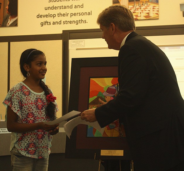 Himaja Kotti accepts a check from Superintendent Ron Thiele for the purchase of her painting 'A Need of Water.'